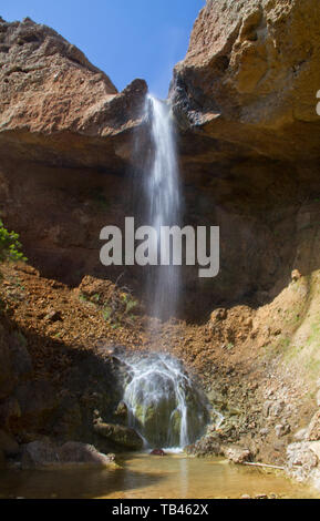 Small waterfall splashing down in a small pool in a rocky landcape Stock Photo
