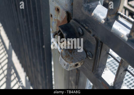 Old and rusty heavy duty pad lock securing aan iron gate, close-up Stock Photo