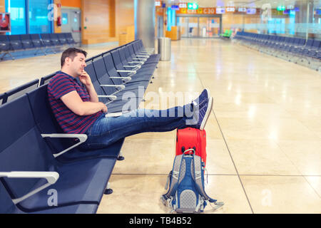 Tired tourist sleeping with legs on suitcase in airport terminal. Stock Photo