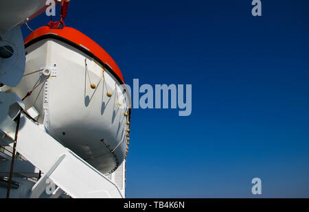 Red and white lifeboat on white steel crane on big farry boat Stock Photo