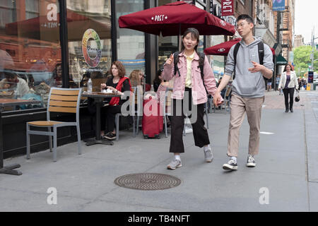 A young Asian couple walk on Broadway in Greenwich Village and engage in animated conversation. Manhattan, New York City. Stock Photo