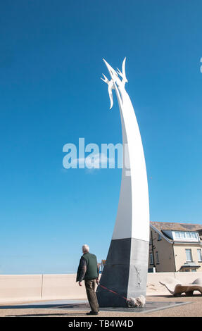 Man and dog next to comtempory artwork of two large white seagulls set against a deep blue sky flying above the town of Cleveleys Lancashire England Stock Photo