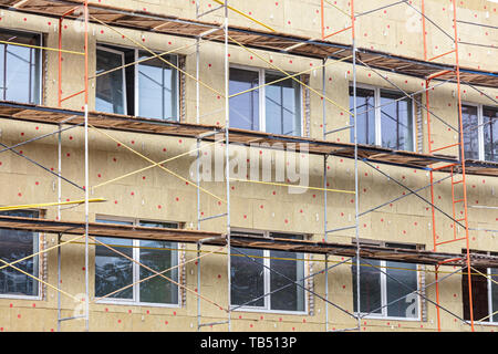 thermal insulation of house wall with mineral wool. scaffolding near facade of a building for restoration Stock Photo