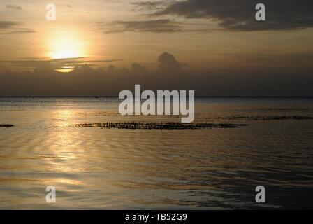 Dull gold colors of sunset with a silhouette of a ship in the distance ...