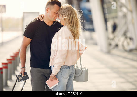 Couple in a airport. Beautiful blonde in a white jacket. Man in a black t-shirt Stock Photo