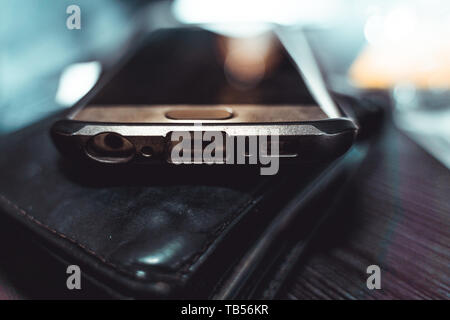 Mobile phone lies on a purse on a table. (Indirect light) Stock Photo