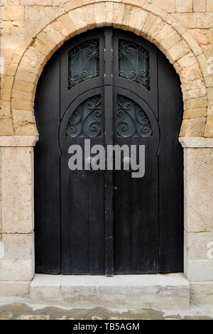 A modern dark wooden door with cast iron designs of an old house in an alleyway in the medina (old city) of Tunis, Tunisia. Stock Photo