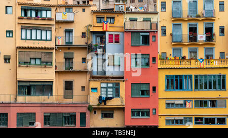 Multi colored houses on the bank of the Onyar River, Girona, Spain. Estelada Blava, flag of Catalonian independence, displayed on balconies and window Stock Photo