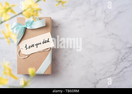 event design concept - top view of fathers day layout with handwriting calligraphy, kraft gift box and yellow dancing doll orchid flower on white marb Stock Photo