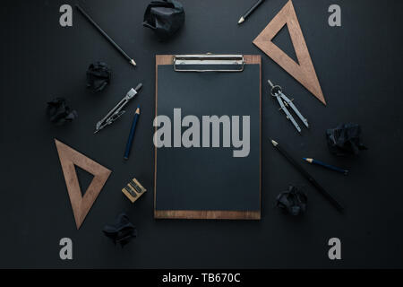 Black on black flat lay with a clipboard, pencils, and rulers. Drawing blueprints header with copy space. Stock Photo