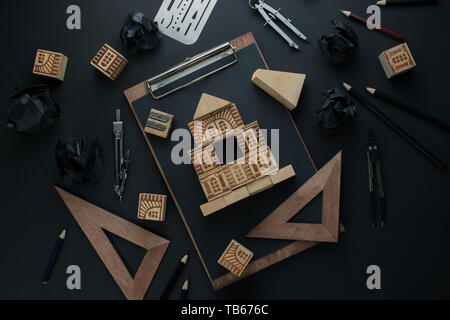 House construction, planning, and repairment concept. Wooden block home on a clipboard with engineering equipment, compasses, rulers and pencils. Work Stock Photo