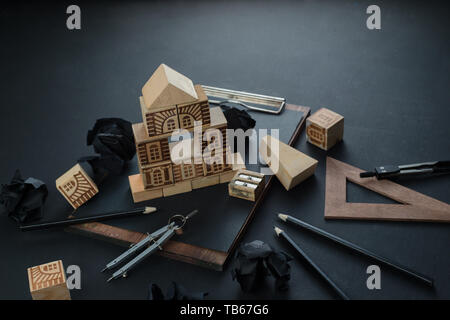 Constructing a house, real estate planning and studying architecture concept. Dark header with toy wooden blocks, small house, pencils and copy space. Stock Photo