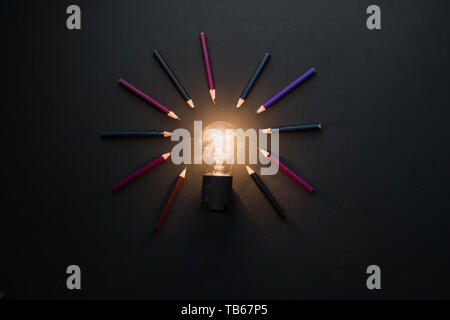 Light bulb shining in black on black flat lay with pencils. The idea for engineering, building or construction concept with copy space. Stock Photo