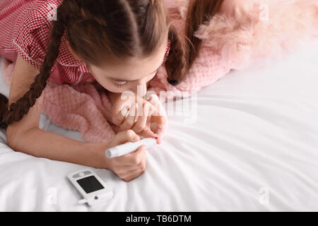 Diabetic girl taking blood sample with lancet pen at home Stock Photo