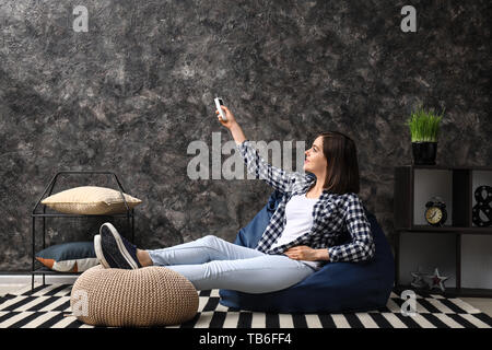 Young woman switching on air conditioner at home Stock Photo