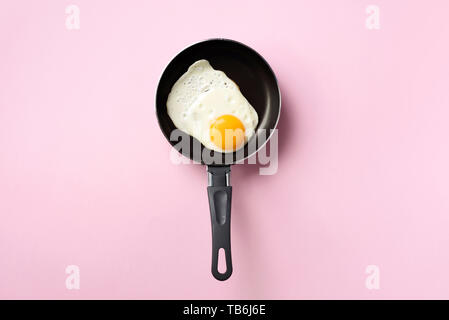 Creative food concept with fried egg on pan over pink background. Top view. Creative pattern in minimal style. Flat lay Stock Photo