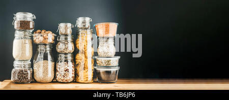 Banner with assortment of uncooked grains, cereals and pasta in glass jars on wooden table. Healthy cooking, clean eating, zero waste concept. Balance Stock Photo