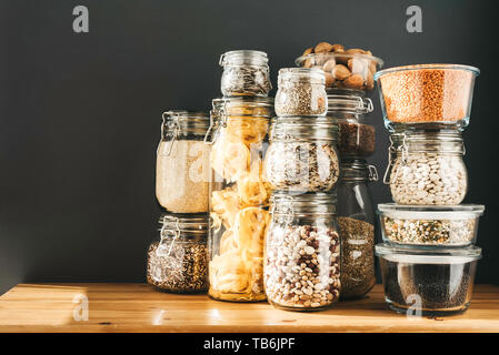 Assortment of grains, cereals and pasta in glass jars on wooden