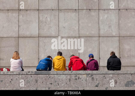 young people sitting on a wall at the Roman-Germanic Museum, Cologne, Germany.  Jugendliche sitzen auf einer Mauer am Roemisch-Germanischen Museum, Ko Stock Photo