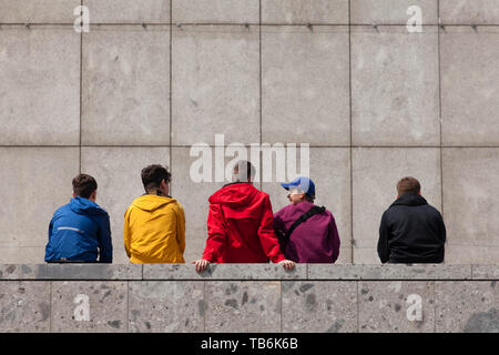 young people sitting on a wall at the Roman-Germanic Museum, Cologne, Germany.  Jugendliche sitzen auf einer Mauer am Roemisch-Germanischen Museum, Ko Stock Photo