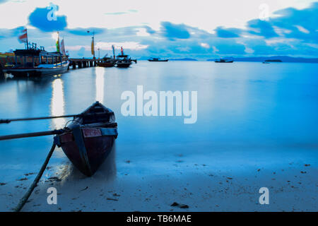 Long exposure shot of the ocean and a pier in a blue time with the old boats defocused. uploaded at Bandar Lampung. Indonesia in May 2019. Stock Photo