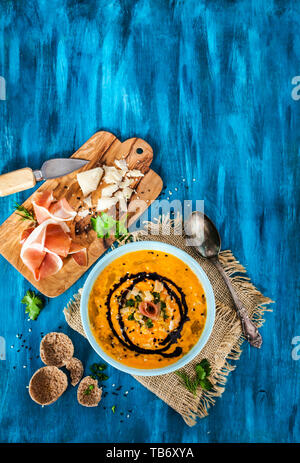 Pumpkin cream soup bowl, served with sesame,  prosciutto, parmesan cheese, olive oil, balsamic and herbs Stock Photo