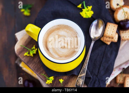 Bright yellow mug of fresh hot black coffee and sweets on summer rustic background Stock Photo
