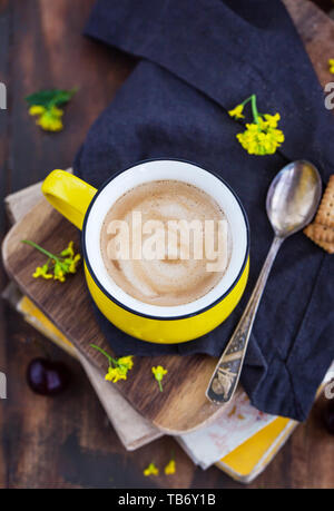 Bright yellow mug of fresh hot black coffee and sweets on summer rustic background Stock Photo