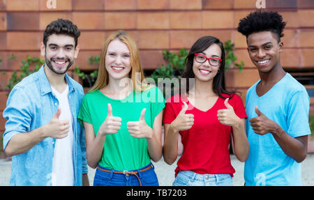 Group of four young adults of generation y showing thumbs outdoor in the summer in the city Stock Photo