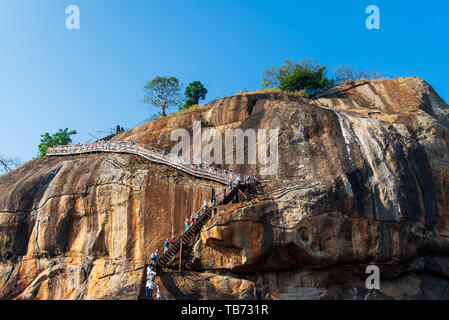 Sigiriya, Sri Lanka - March 31, 2019: Sigiriya ancient rock fortress in Sri Lanka with tourists climbing the stairs on a sunny day Stock Photo