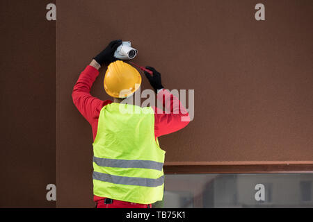 Professional cctv technician working.Technician Fixing Camera On Wall Stock Photo