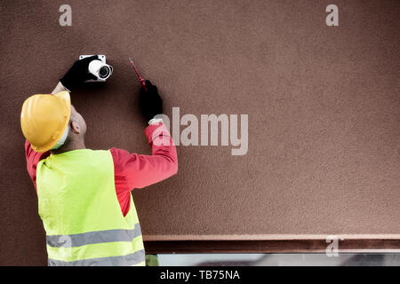 Professional cctv technician working.Technician Fixing Camera On Wall Stock Photo