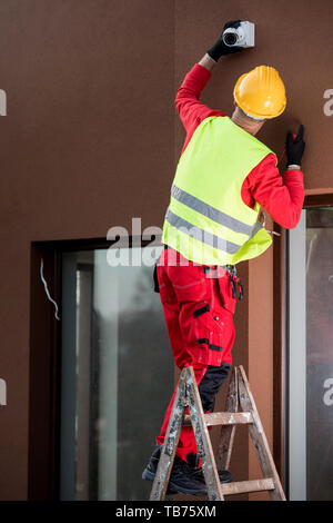 Professional cctv technician working.Technician Fixing Camera On Wall Stock Photo