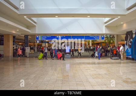 Orlando, Florida.  March 01, 2019. People walking with baggage to different terminals and top view of Ticketing and Check-in blue sign at Orlando Inte Stock Photo