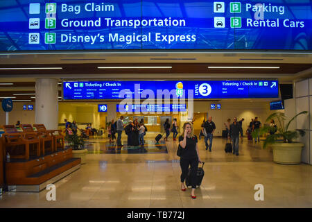 Orlando, Florida.  March 01, 2019. Top view of Bag Claim, Ticketing and Check-in blue signs and woman walking with baggage at Orlando International Ai Stock Photo