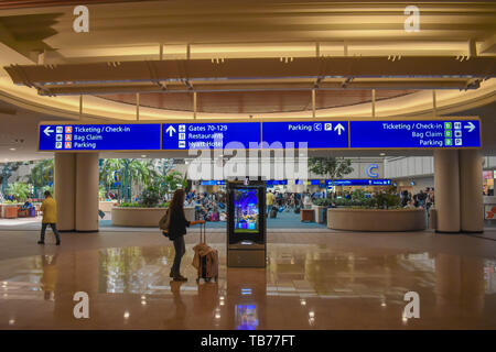 Orlando, Florida.  March 01, 2019. Woman looking at Visitor Center screen and top view of Ticketing and Check-in blue sign at Orlando International Ai Stock Photo