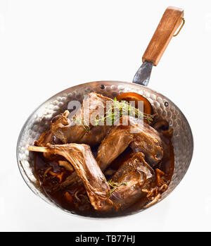 Roasted wild rabbit venison portions flavored with fresh orange, zest and mushrooms served in a pan topped with herbs isolated on white Stock Photo