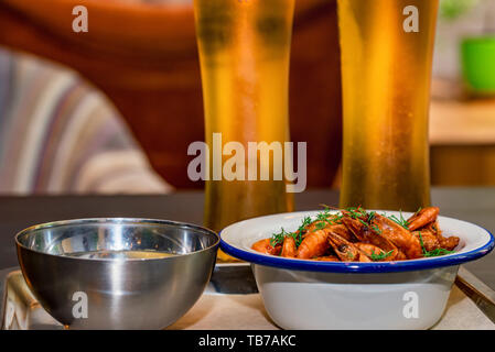 Prepared shrimps with dill in bowl on table with two beer glasses and water Stock Photo