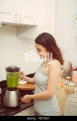 Vegetable smoothie woman blending green smoothies with blender home in kitchen