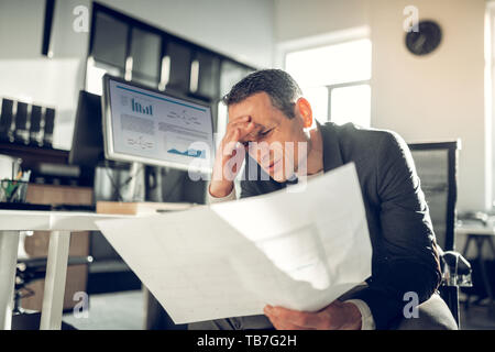 Dark-haired businessman suffering from headache after exhausting day Stock Photo