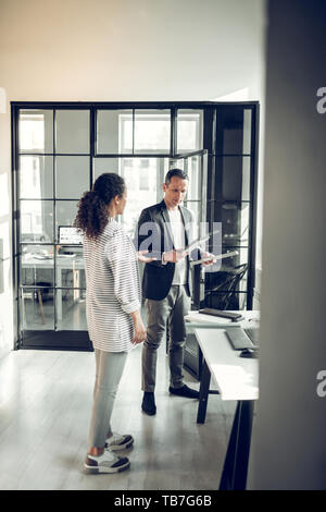 Stylish curly trainee coming to her serious boss in the office Stock Photo