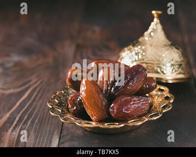 Metal plate of dates on dark wooden table. Dried dates with copy space. Stock Photo