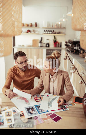Sharing ideas. Two fashion designers discussing sketches of clothes for their new collection. Stock Photo