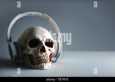 Human skull with headphones on grey background Stock Photo