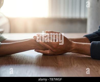 Friends holding each other's hand on desk Stock Photo