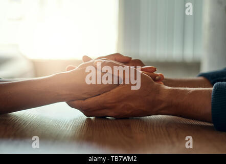 Couple holding their hands on desk Stock Photo