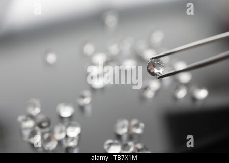 The jeweler holds a diamond in tweezers Stock Photo