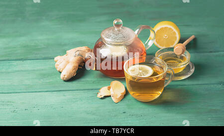Tea lemon ginger with honey in a glass cup and a teapot on a wooden rustic background. Healthy drink for detox health. Stock Photo
