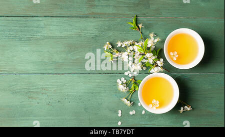 Fragrant flower tea with petals in white porcelain cups on wooden background. Flat layout top view. Copy space. Stock Photo