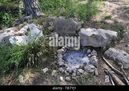 burnt out campfire in a fire pit. stones in a circle around the fire is to prevent the fire from spreading Stock Photo